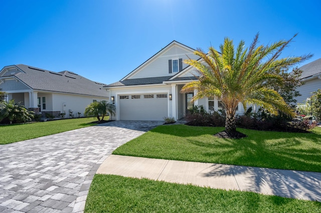 view of front of home featuring decorative driveway, a garage, and a front yard