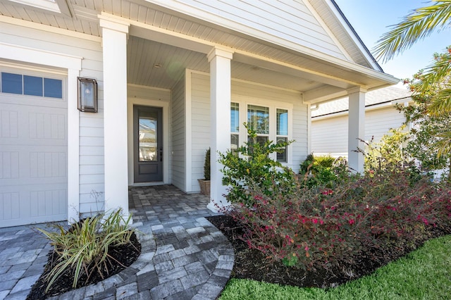 view of exterior entry featuring a porch and an attached garage