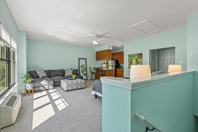 living room with a wall unit AC, ceiling fan, and carpet