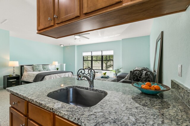 carpeted bedroom with ceiling fan and sink