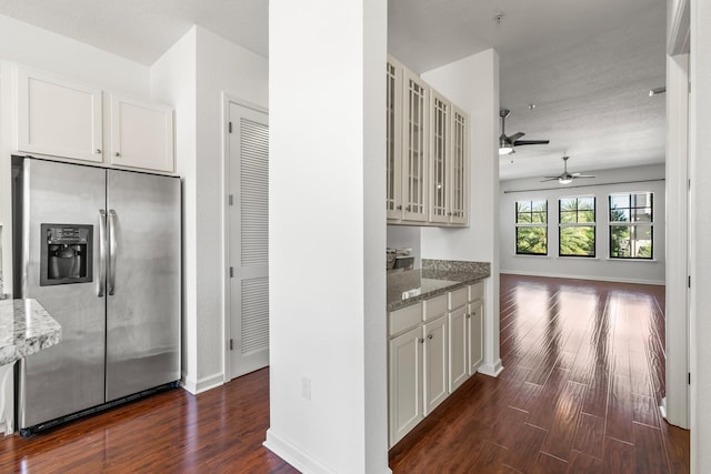 kitchen featuring stainless steel fridge, white cabinets, light stone countertops, and dark hardwood / wood-style floors