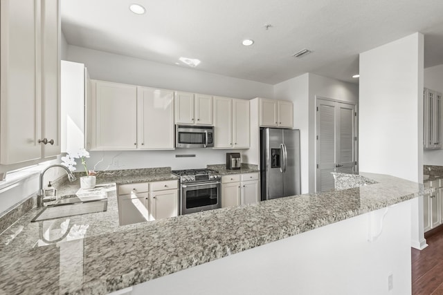 kitchen featuring dark hardwood / wood-style floors, light stone counters, white cabinetry, and stainless steel appliances