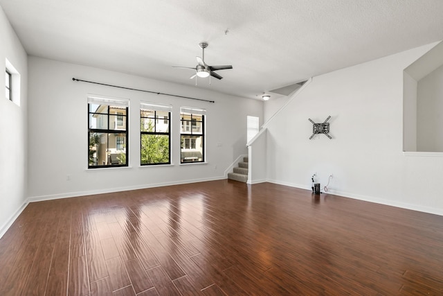 unfurnished living room featuring a textured ceiling, ceiling fan, and dark wood-type flooring