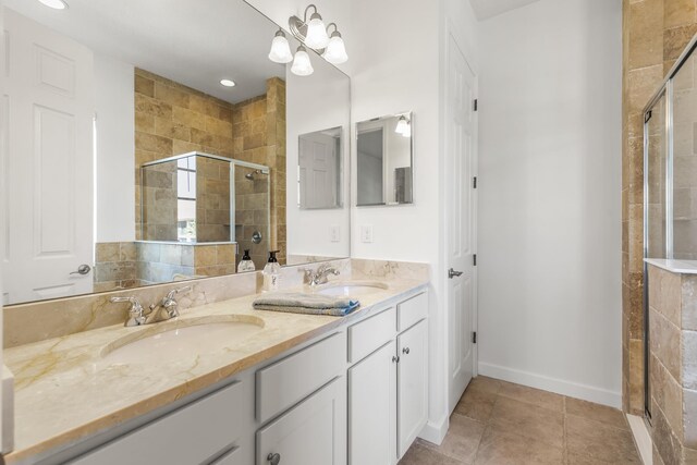 bathroom with tile patterned floors, a shower with door, vanity, and a notable chandelier