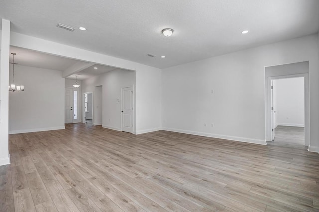 unfurnished living room featuring light wood finished floors, a notable chandelier, and baseboards