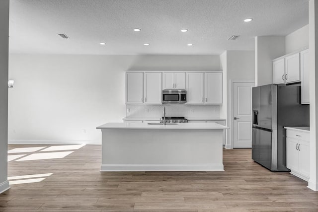 kitchen with backsplash, a textured ceiling, appliances with stainless steel finishes, and light countertops