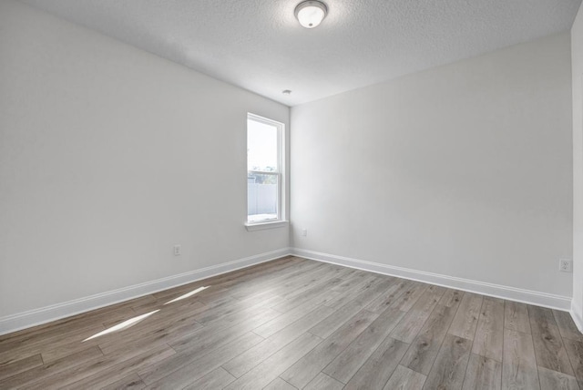 unfurnished room featuring a textured ceiling, wood finished floors, and baseboards