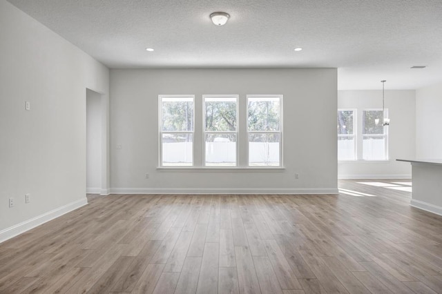 unfurnished living room featuring wood finished floors, a chandelier, and a textured ceiling