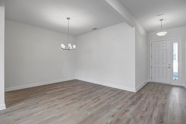 entrance foyer with an inviting chandelier, baseboards, wood finished floors, and visible vents