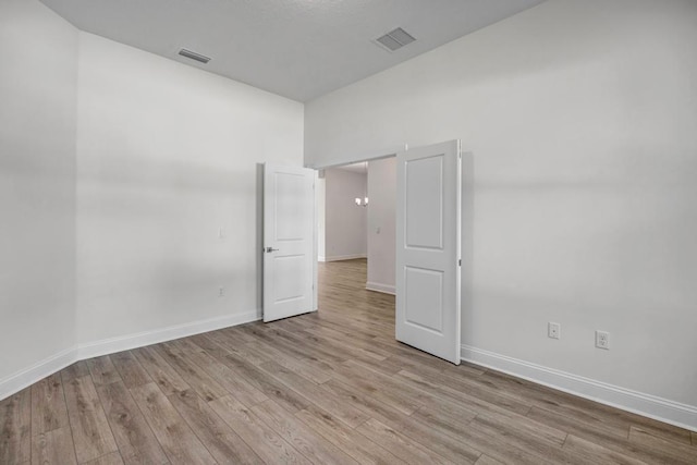 spare room with visible vents, light wood-style flooring, and baseboards