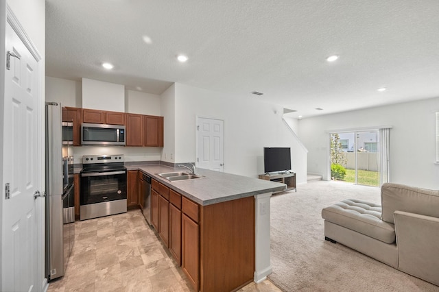 kitchen featuring kitchen peninsula, a textured ceiling, stainless steel appliances, light colored carpet, and sink