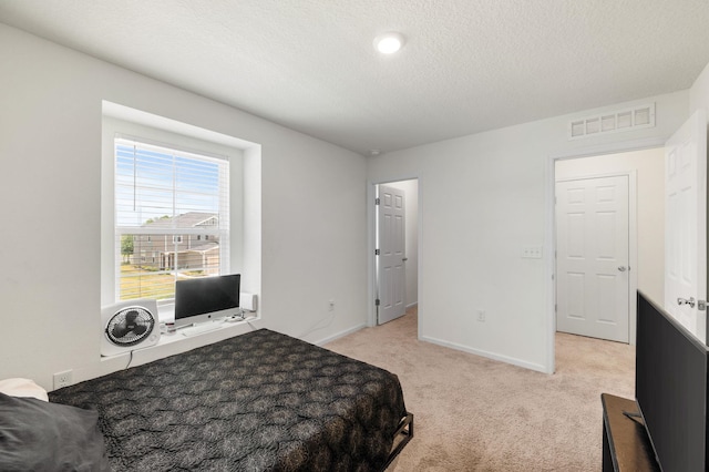 bedroom featuring light carpet and a textured ceiling