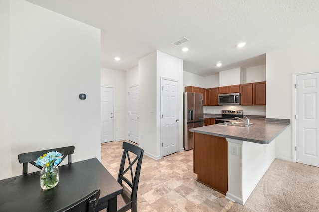 kitchen featuring light carpet, sink, a textured ceiling, kitchen peninsula, and stainless steel appliances