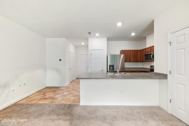 kitchen featuring kitchen peninsula, appliances with stainless steel finishes, light carpet, a textured ceiling, and sink