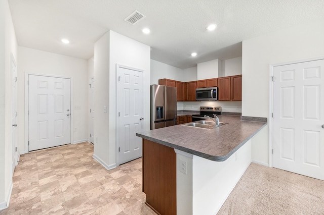 kitchen with sink, kitchen peninsula, a textured ceiling, light carpet, and appliances with stainless steel finishes