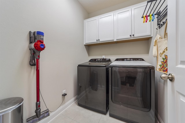 laundry room with cabinets, light tile patterned floors, and washing machine and clothes dryer