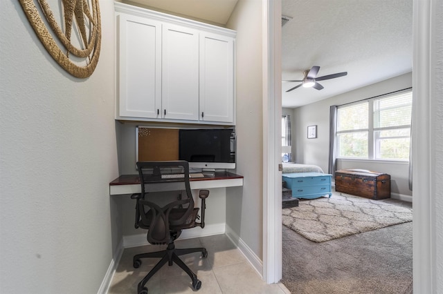 carpeted home office with ceiling fan and built in desk