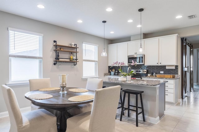 kitchen featuring stone counters, white cabinets, stainless steel appliances, and decorative light fixtures