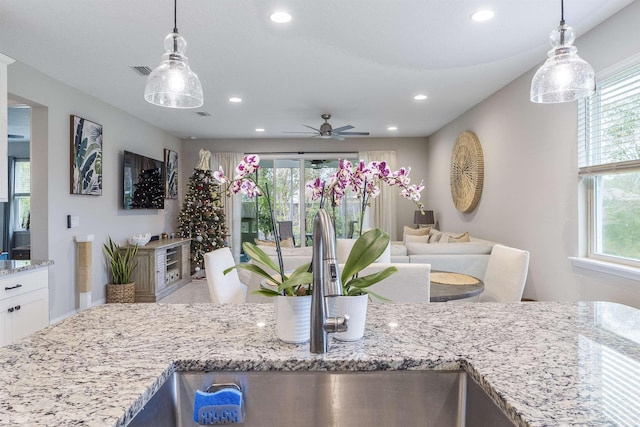 kitchen featuring decorative light fixtures, light stone countertops, and a wealth of natural light