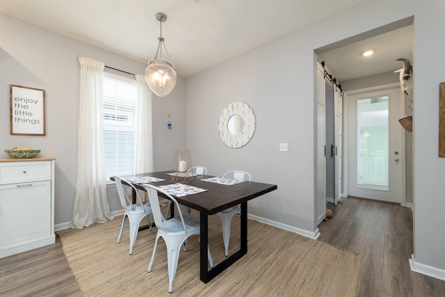 dining area with a barn door and light wood-type flooring