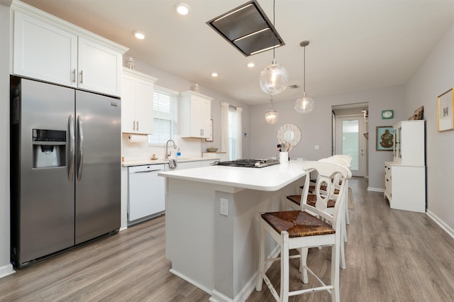 kitchen with stainless steel appliances, a kitchen island, light hardwood / wood-style flooring, pendant lighting, and white cabinets