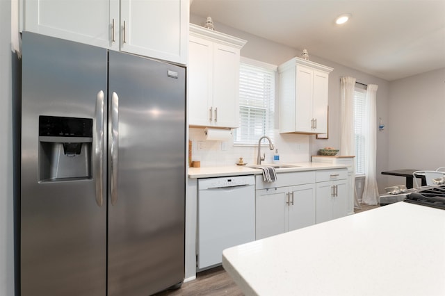 kitchen with decorative backsplash, stainless steel refrigerator with ice dispenser, white cabinets, sink, and dishwasher