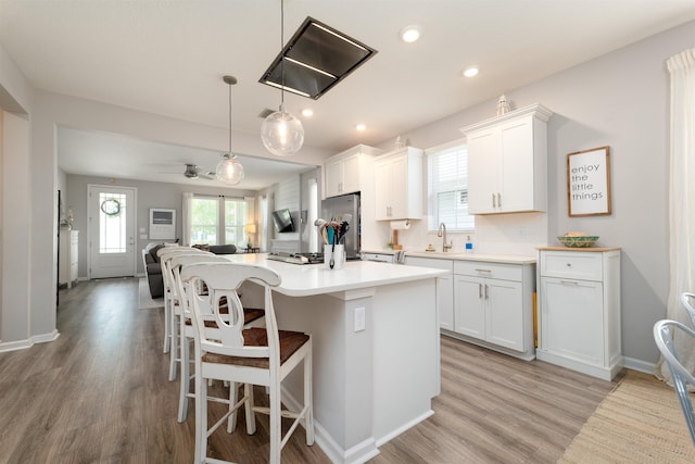 kitchen with stainless steel refrigerator, a center island, light hardwood / wood-style floors, decorative light fixtures, and white cabinets