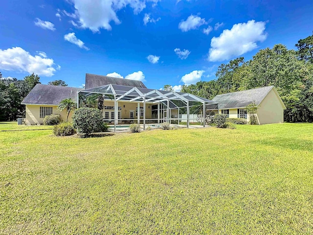 back of house with a lanai and a lawn