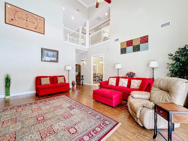 living room featuring wood-type flooring, a towering ceiling, and ornamental molding