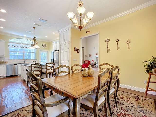 dining room featuring sink, crown molding, a chandelier, a textured ceiling, and light wood-type flooring