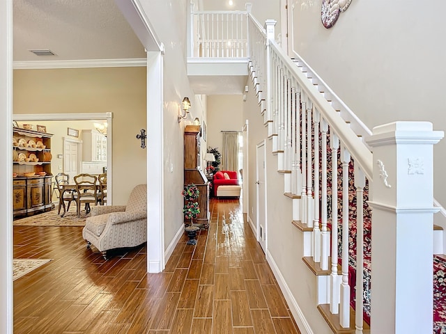 entryway with a towering ceiling, hardwood / wood-style flooring, and ornamental molding