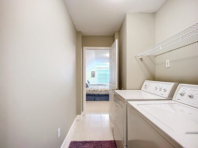 laundry area featuring light tile patterned floors, a textured ceiling, and separate washer and dryer