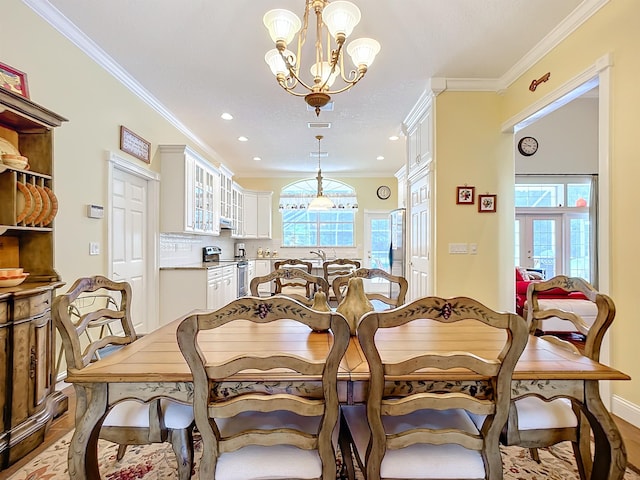 dining area with a notable chandelier, plenty of natural light, crown molding, and light hardwood / wood-style flooring