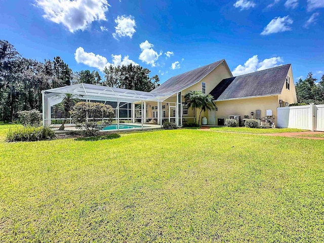 rear view of property featuring a lanai, a yard, and central AC unit