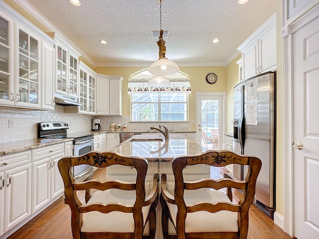 kitchen featuring decorative light fixtures, light stone countertops, ornamental molding, and appliances with stainless steel finishes