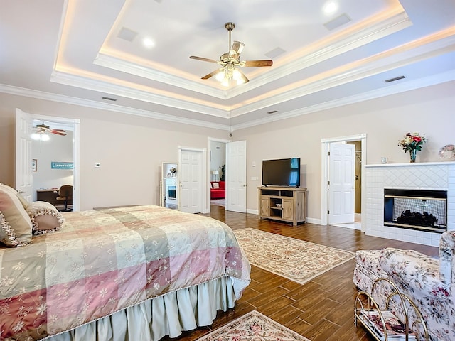 bedroom with ornamental molding, a tray ceiling, ceiling fan, and dark wood-type flooring