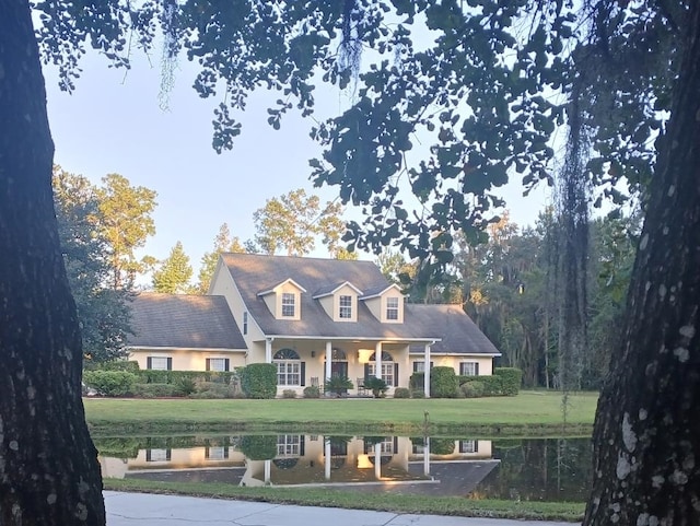 cape cod home with a front lawn and a water view