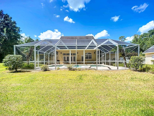 rear view of house featuring glass enclosure and a lawn