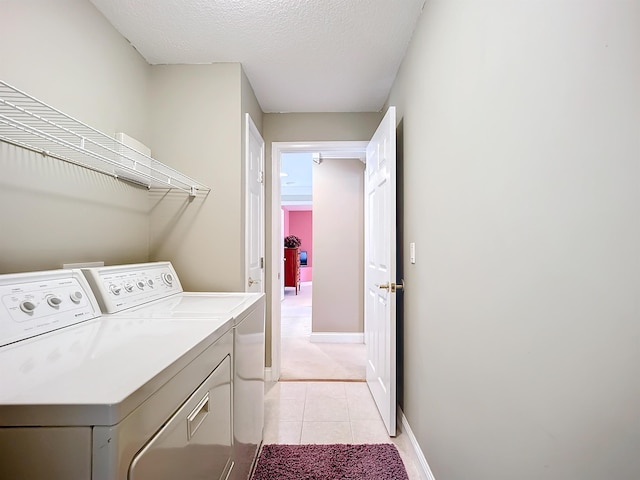 washroom with washer and clothes dryer, light tile patterned floors, and a textured ceiling