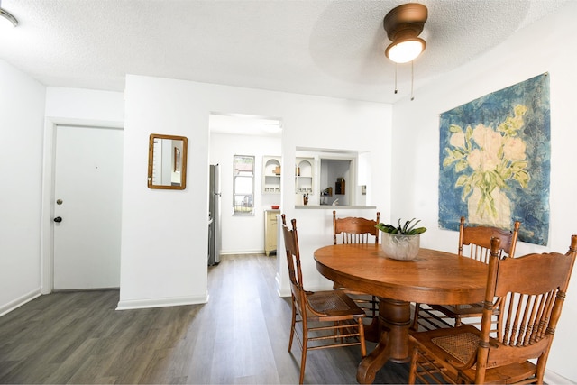 dining area with ceiling fan, dark wood-type flooring, and a textured ceiling