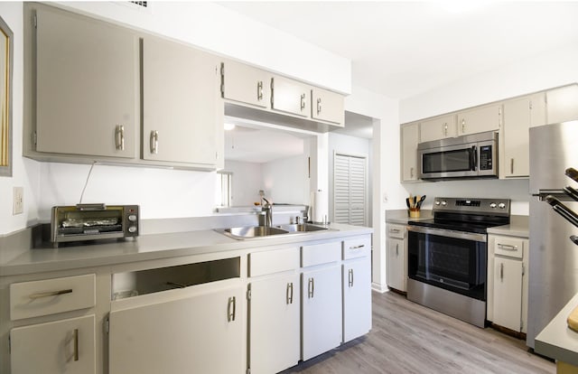 kitchen featuring appliances with stainless steel finishes, light hardwood / wood-style flooring, and sink