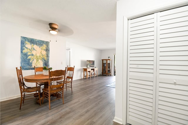 dining space with ceiling fan and dark wood-type flooring