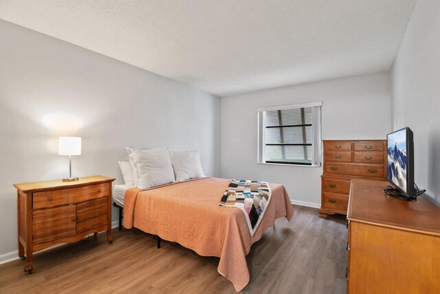 bedroom with a textured ceiling and dark hardwood / wood-style flooring