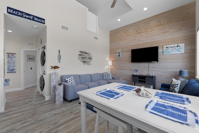 12 13th St, Saint Augustine Beach, FL 32080 - living room featuring an accent wall, stacked washer / dryer, ceiling fan, wood walls, and visible vents