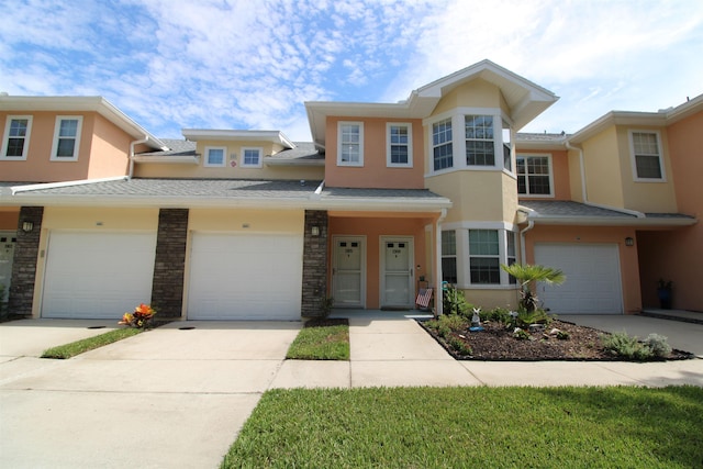 view of property with stucco siding, a garage, and concrete driveway