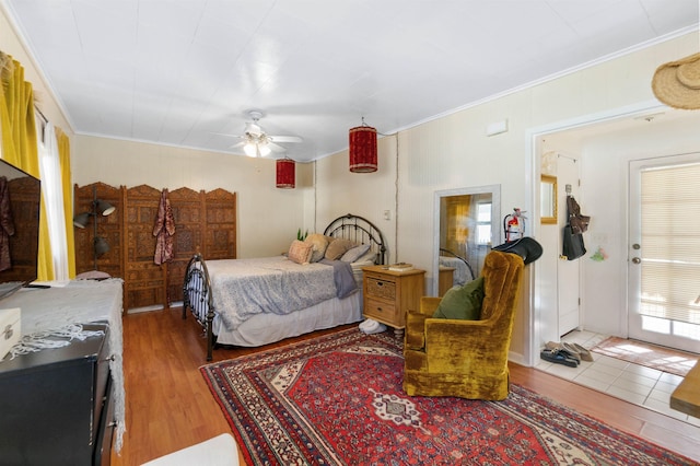 bedroom featuring ceiling fan, wood-type flooring, crown molding, and multiple windows