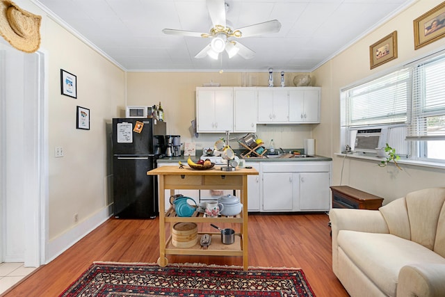 kitchen featuring white cabinets, black fridge, crown molding, and light hardwood / wood-style flooring