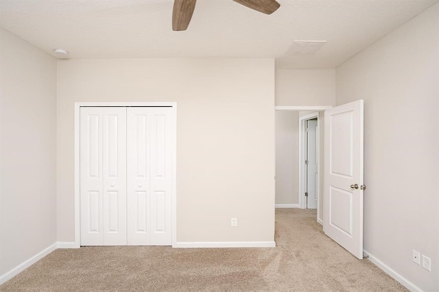 unfurnished bedroom featuring light carpet, a closet, and ceiling fan