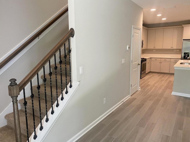 staircase featuring wood-type flooring and sink