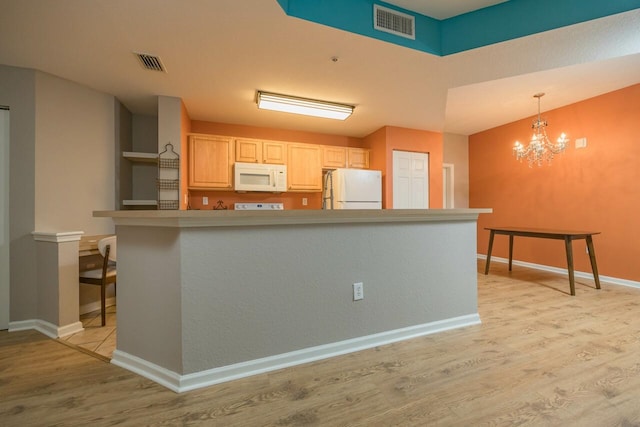 kitchen featuring light brown cabinetry, a chandelier, hanging light fixtures, white appliances, and light wood-type flooring